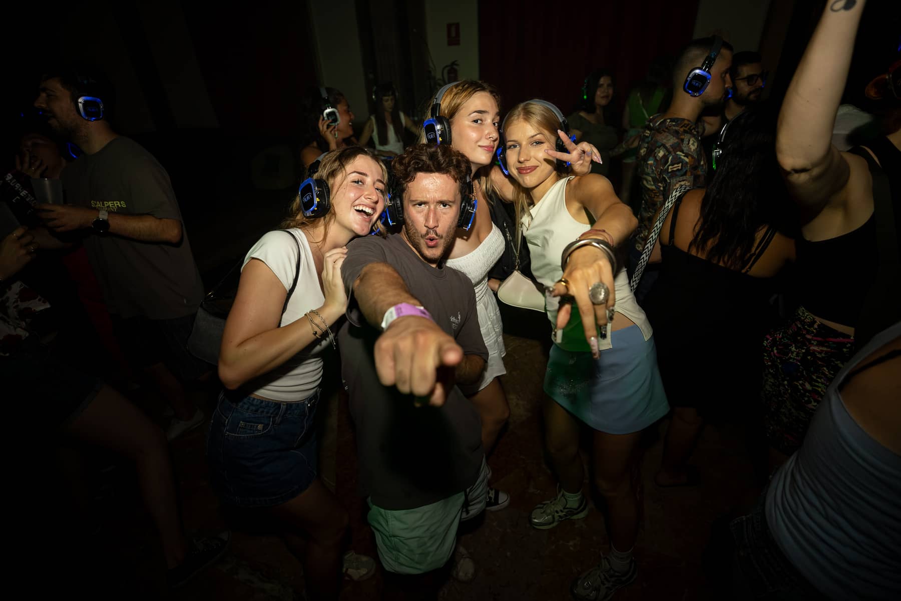 Una multitud bailando con auriculares AURA iluminados en un silent disco