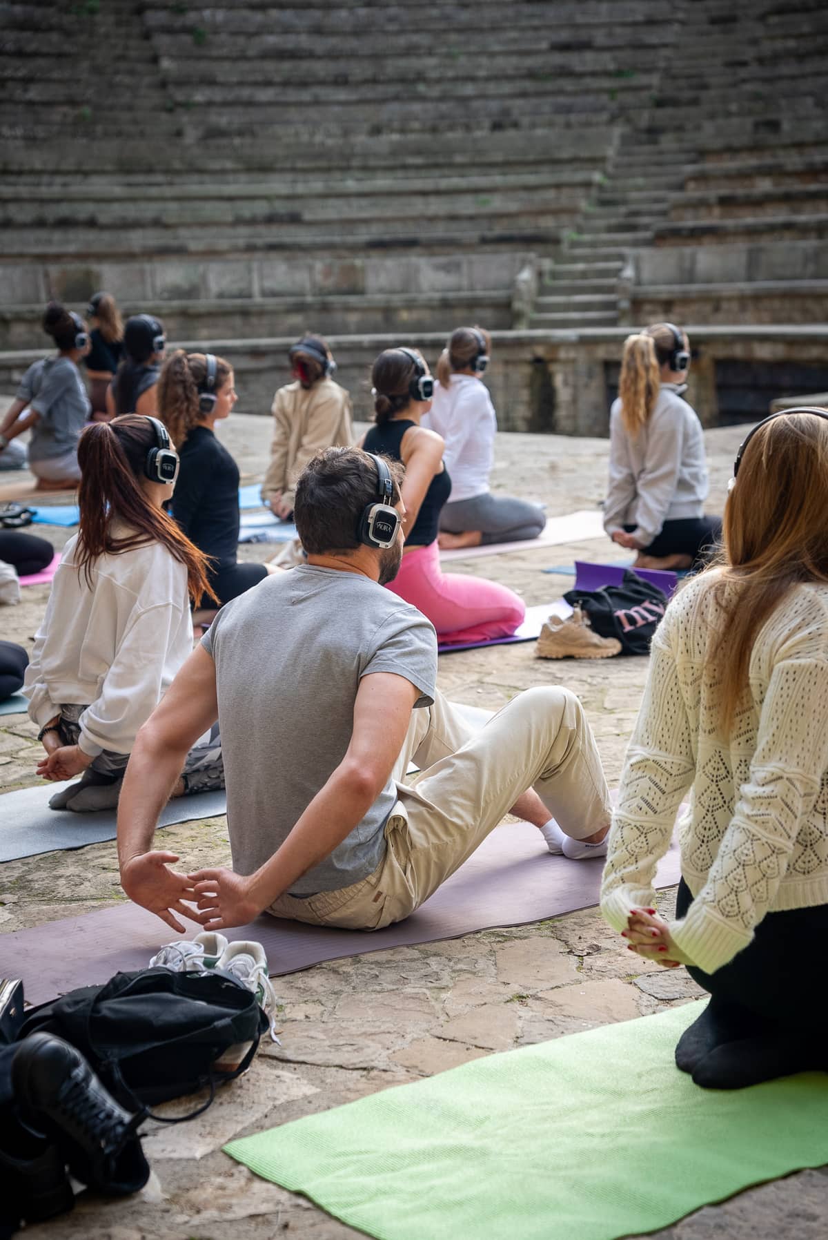 Personas haciendo yoga con auriculares AURA en un anfiteatro al aire libre